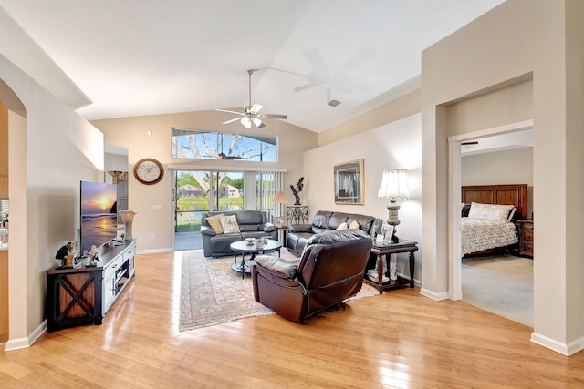 living room featuring visible vents, baseboards, ceiling fan, light wood-style floors, and high vaulted ceiling