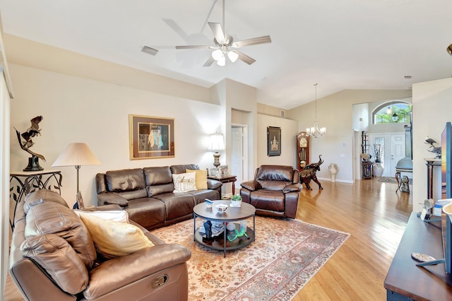 living room featuring visible vents, ceiling fan with notable chandelier, light wood-style flooring, and vaulted ceiling