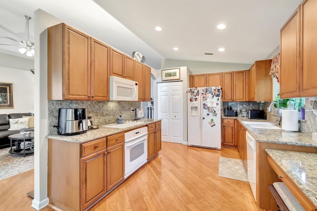 kitchen with light wood finished floors, white appliances, lofted ceiling, and a sink