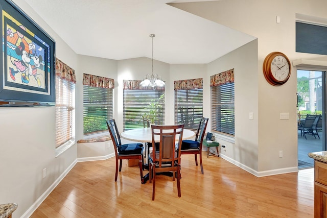 dining area with light wood finished floors, plenty of natural light, lofted ceiling, and an inviting chandelier