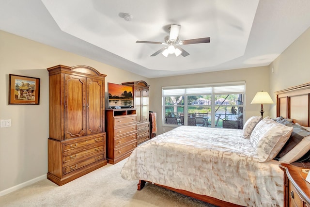 bedroom featuring ceiling fan, baseboards, light carpet, a raised ceiling, and access to outside