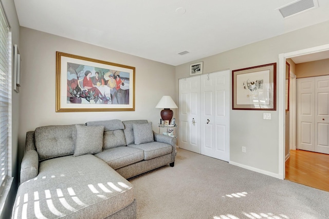 carpeted living area with baseboards and visible vents