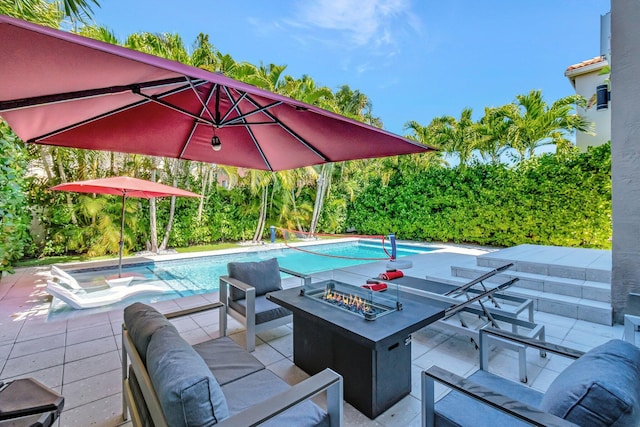 view of patio featuring an outdoor pool and an outdoor living space with a fire pit