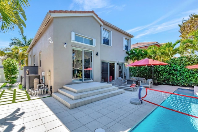 back of property with a patio, an outdoor pool, stucco siding, a tile roof, and an outdoor hangout area