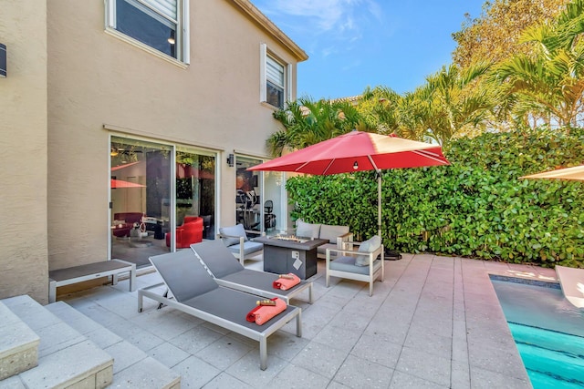 view of patio with an outdoor living space with a fire pit