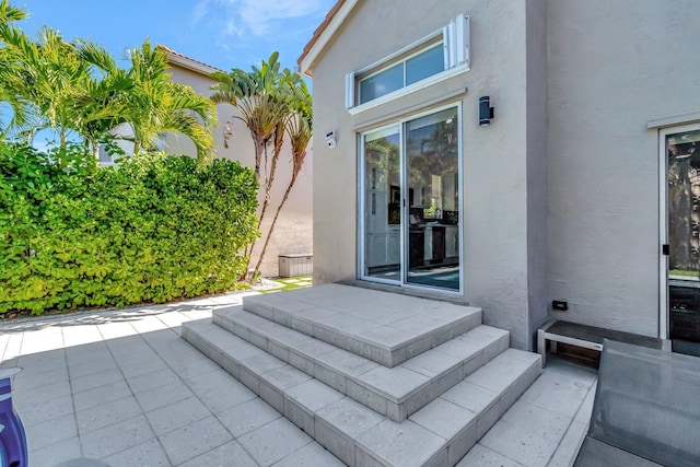 doorway to property featuring a patio area and stucco siding