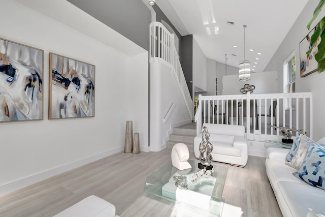 living area with baseboards, stairs, recessed lighting, a high ceiling, and wood finished floors