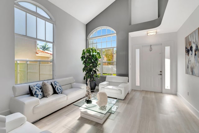 living area with high vaulted ceiling and baseboards