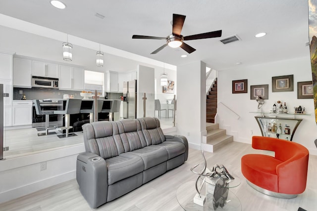 living room with recessed lighting, visible vents, baseboards, and stairs