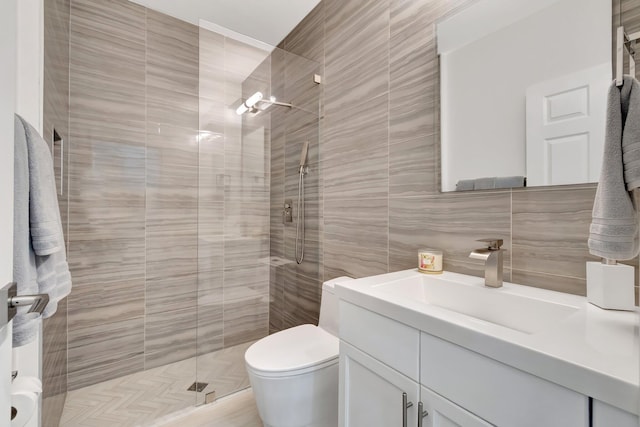 full bathroom with vanity, a shower stall, tile walls, toilet, and tasteful backsplash