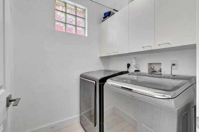 washroom with washing machine and dryer, cabinet space, and baseboards