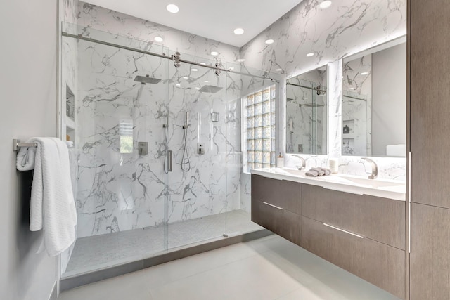 full bath with a marble finish shower, recessed lighting, double vanity, and a sink