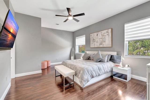 bedroom featuring visible vents, a ceiling fan, baseboards, and dark wood-style flooring