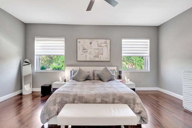 bedroom featuring baseboards, multiple windows, dark wood-type flooring, and ceiling fan