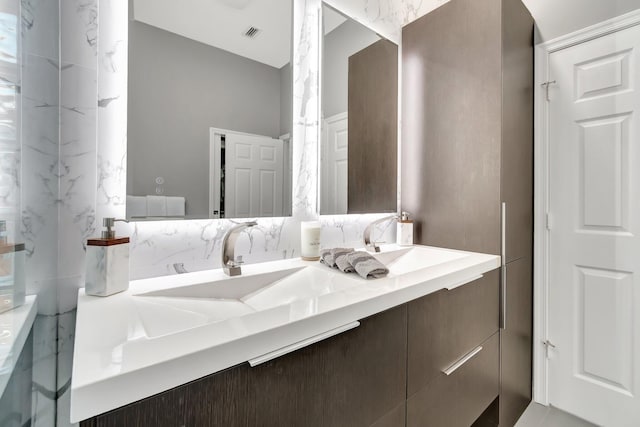 full bath with a sink, visible vents, tasteful backsplash, and double vanity