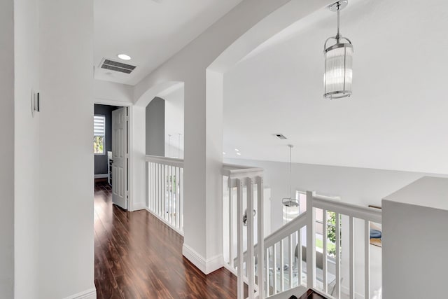 hallway featuring visible vents, a healthy amount of sunlight, baseboards, and wood finished floors