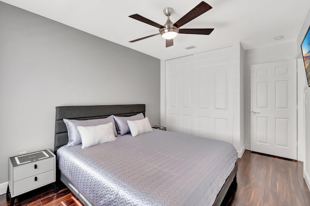 bedroom featuring dark wood finished floors, visible vents, baseboards, and a closet