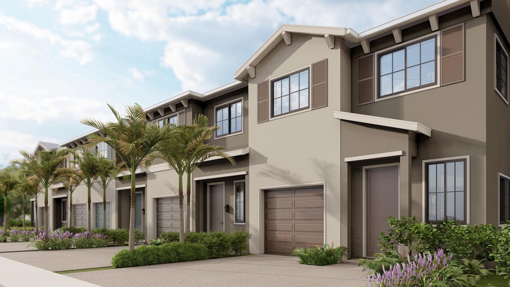 view of property featuring stucco siding, a garage, and driveway