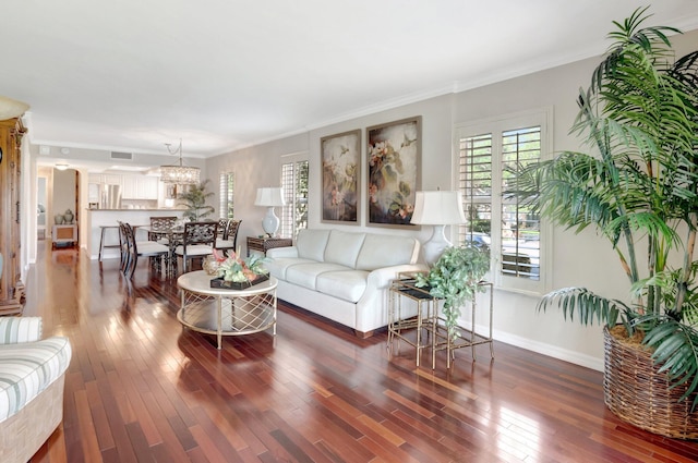 living room with a notable chandelier, crown molding, baseboards, and wood finished floors