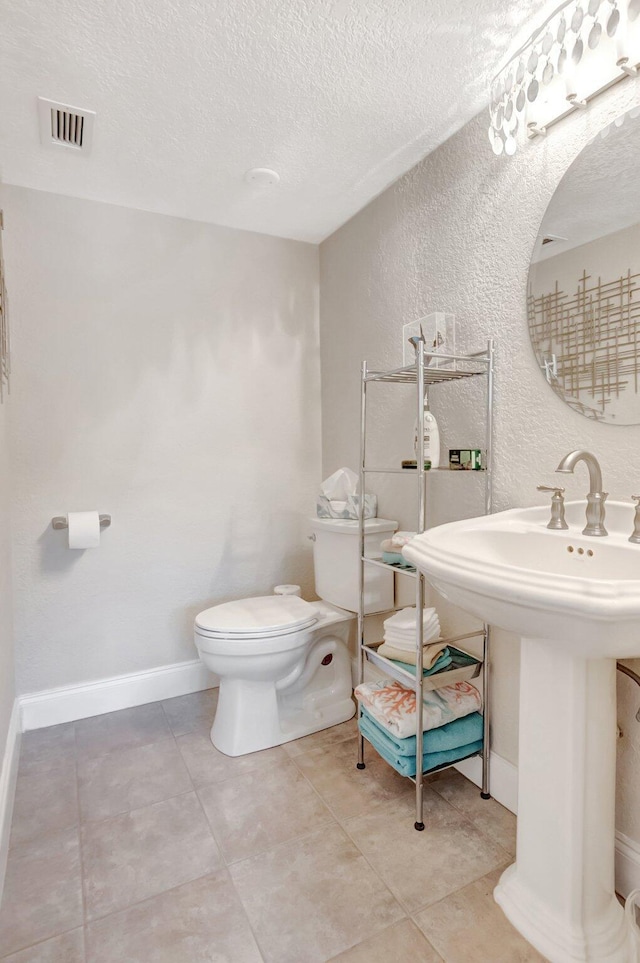 bathroom featuring visible vents, toilet, a textured ceiling, baseboards, and a textured wall