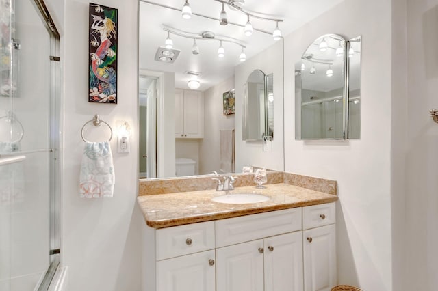 full bathroom featuring toilet, vanity, and a shower with shower door