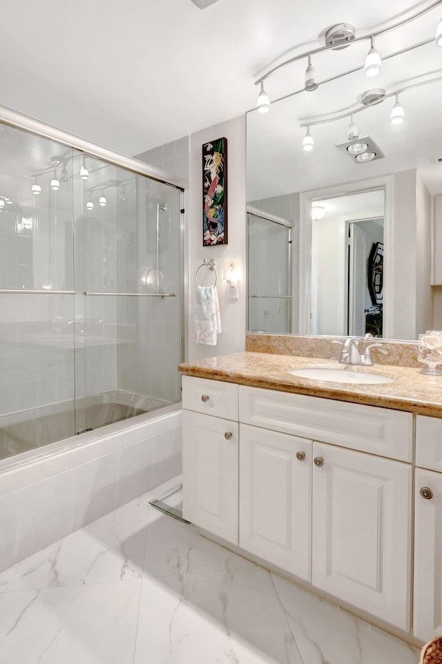 bathroom with enclosed tub / shower combo, marble finish floor, and vanity