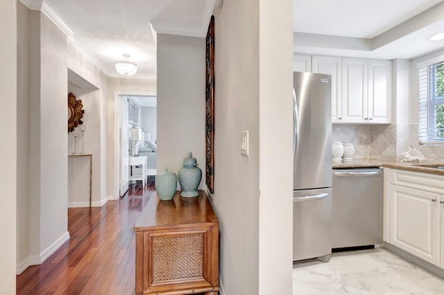 kitchen featuring white cabinets, tasteful backsplash, appliances with stainless steel finishes, and ornamental molding