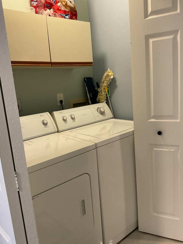 clothes washing area with washing machine and dryer and cabinet space