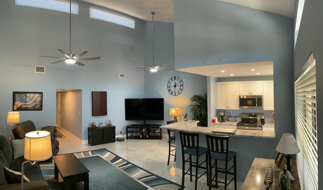 living area with recessed lighting, visible vents, baseboards, and a high ceiling