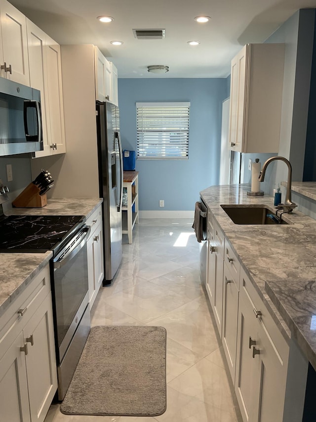 kitchen with light stone countertops, baseboards, recessed lighting, a sink, and appliances with stainless steel finishes