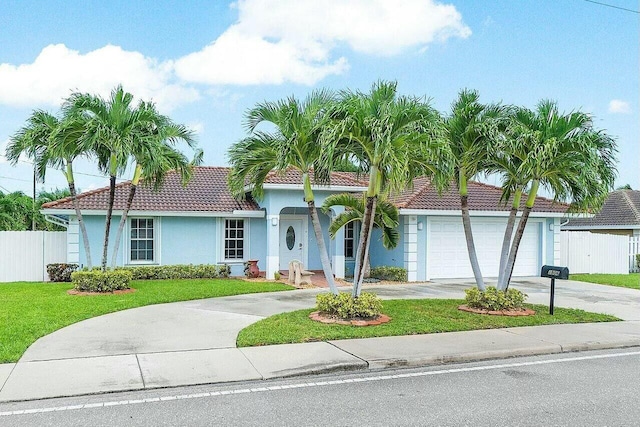 view of front facade featuring a front yard, fence, driveway, a garage, and a tiled roof