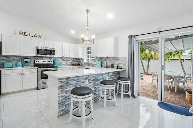 kitchen with stainless steel appliances, lofted ceiling, light countertops, and white cabinetry