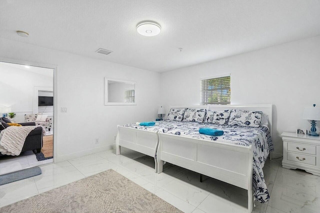 bedroom with visible vents, baseboards, a textured ceiling, and marble finish floor