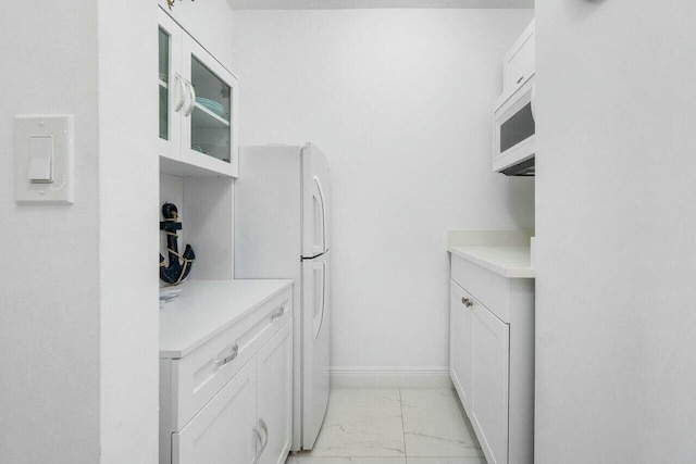 kitchen with marble finish floor, white cabinets, light countertops, and baseboards