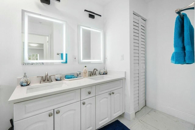 full bathroom with double vanity, marble finish floor, baseboards, and a sink