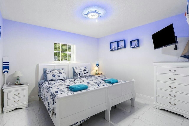 bedroom featuring marble finish floor, a textured ceiling, and baseboards