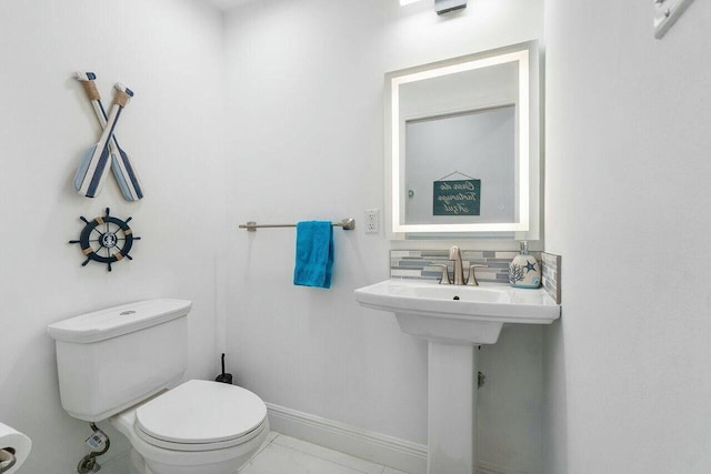 bathroom featuring decorative backsplash, toilet, and baseboards