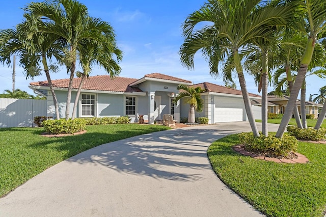 mediterranean / spanish house with stucco siding, a front lawn, fence, concrete driveway, and an attached garage