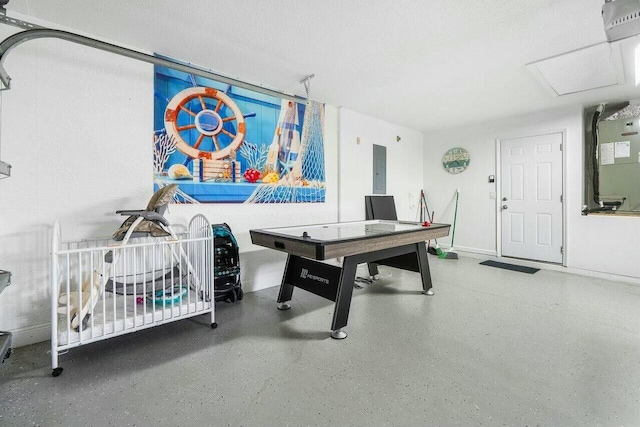 rec room with electric panel, heating unit, a textured ceiling, speckled floor, and baseboards