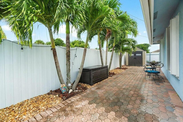 view of patio / terrace featuring an outbuilding, a storage unit, and a fenced backyard