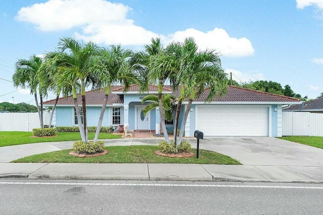 view of front of property featuring a tiled roof, concrete driveway, an attached garage, and fence