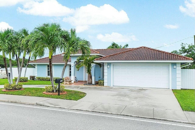 view of front of home featuring a tiled roof, fence, driveway, and stucco siding