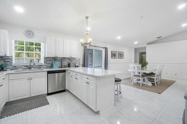 kitchen with a peninsula, white cabinets, stainless steel dishwasher, marble finish floor, and a sink