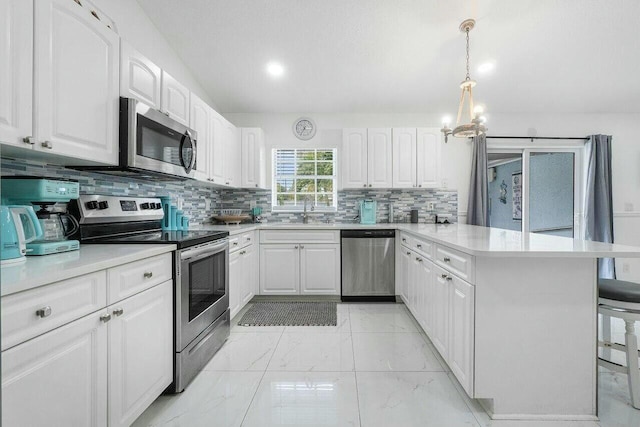 kitchen featuring decorative backsplash, appliances with stainless steel finishes, a peninsula, white cabinets, and marble finish floor