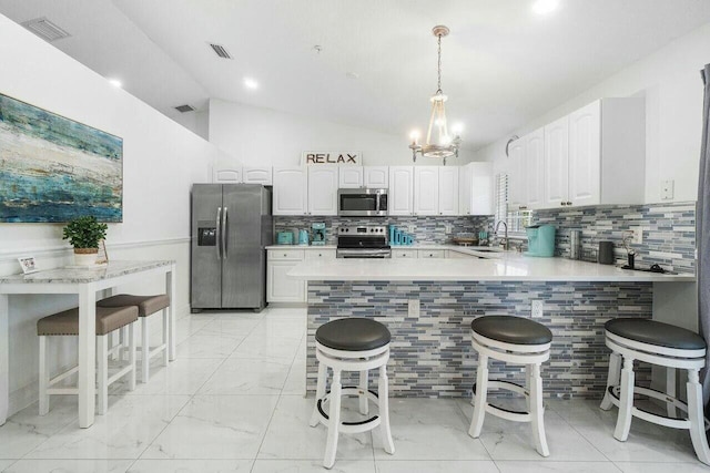 kitchen with visible vents, light countertops, lofted ceiling, appliances with stainless steel finishes, and a peninsula