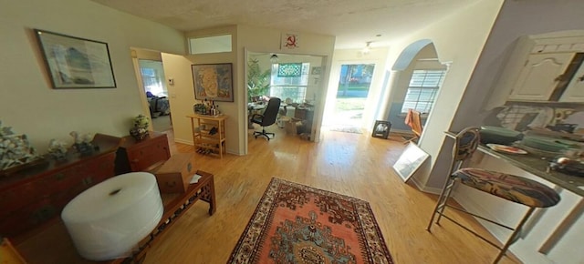 interior space with baseboards, arched walkways, and light wood finished floors