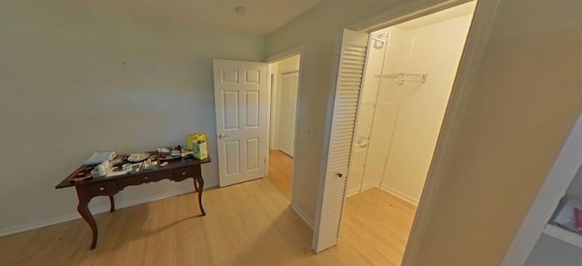 corridor with baseboards and light wood-style floors