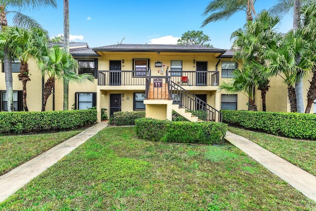 townhome / multi-family property featuring stairs, a front yard, and stucco siding