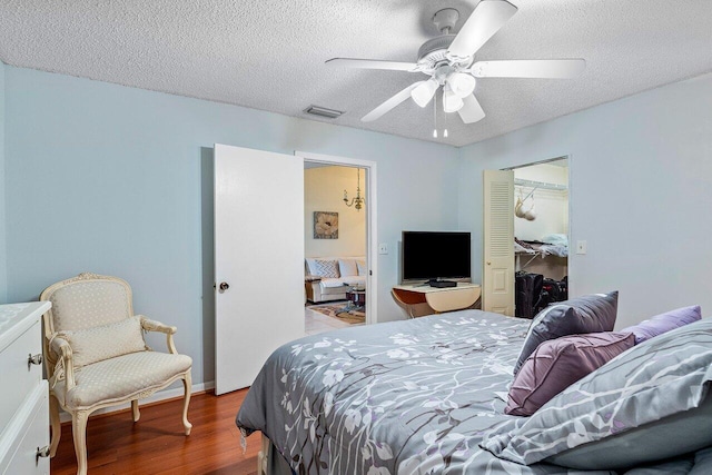 bedroom featuring visible vents, ceiling fan, wood finished floors, a closet, and a textured ceiling