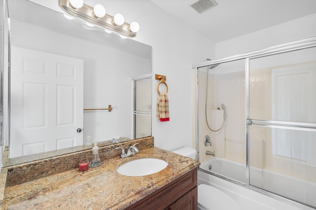 bathroom featuring visible vents, toilet, vanity, and shower / bath combination with glass door